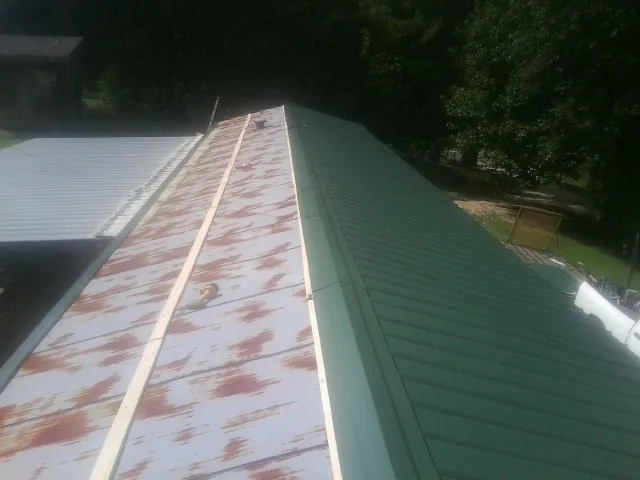Old rusted panels beside newly installed green metal roofing — Wind Damage Roof Repair by Roofing Brothers in Buena Park