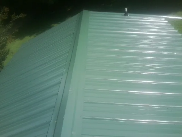 New green metal panels meeting at the ridge of a roof — Flat Roof Repair work by our crew in Buena Park