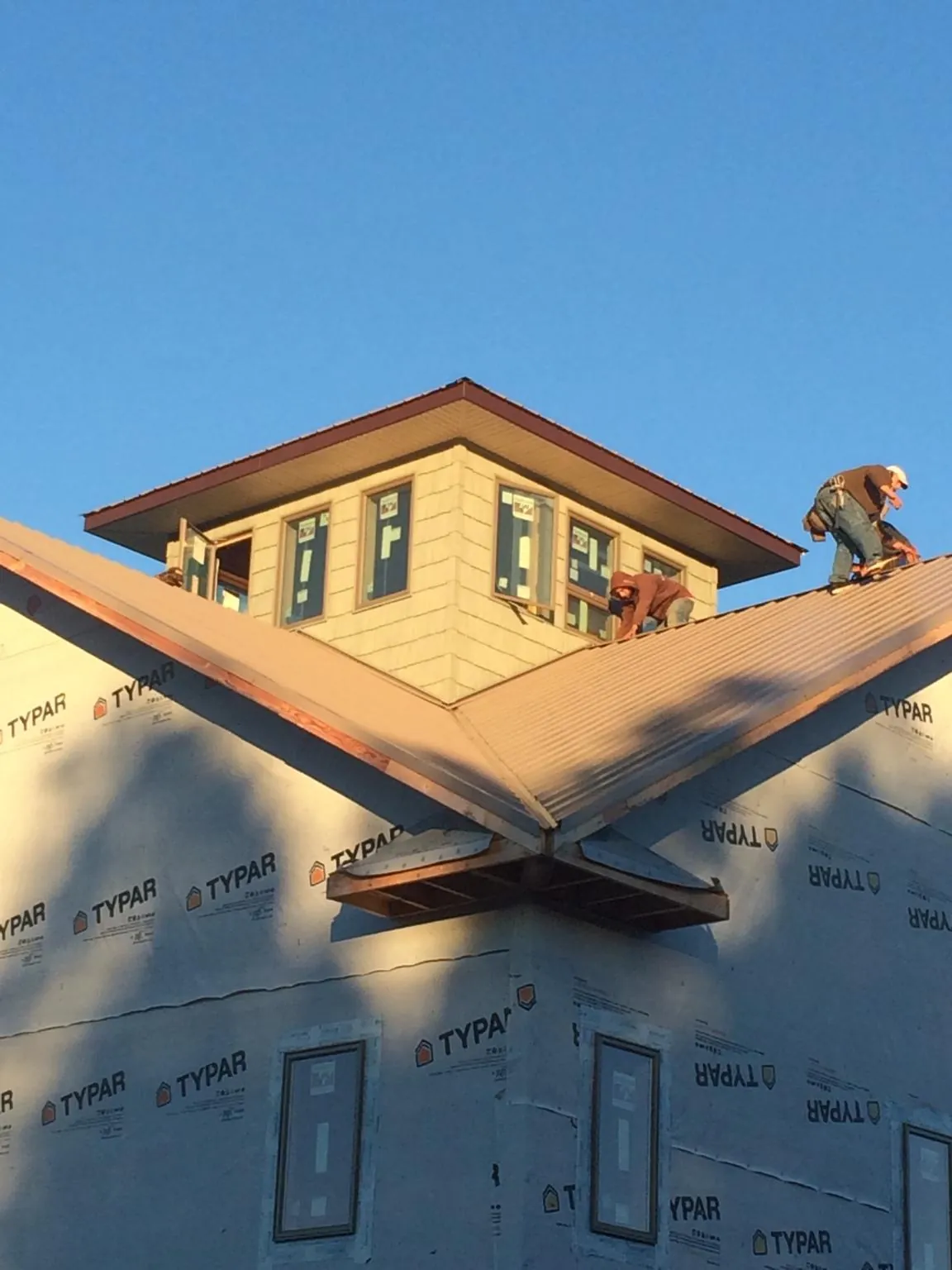 Roofers working around a rooftop cupola on a new metal roof at sunset — Roof Waterproofing in Buena Park by Roofing Brothers